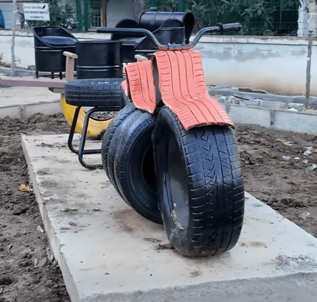 Marmaraereğlisi Belediyesi personeli tarafından atık araba lastiklerinden yapılan turuncu renkli motosiklet figürlü çocuk oyun grubu.