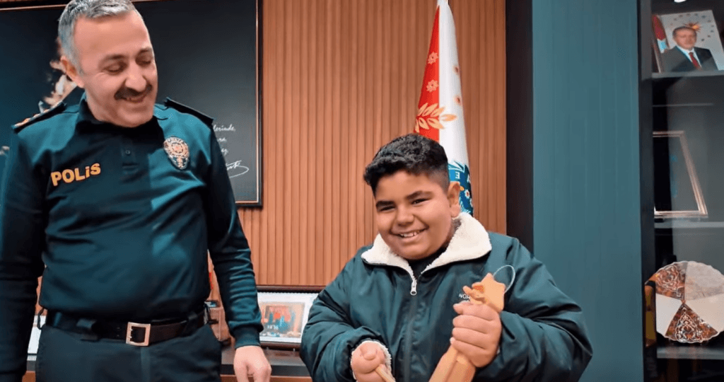 Tekirdağ İl Emniyet Müdürü, makam odasında kendisini ziyaret eden öğrenci grubunu ağırlıyor; bir öğrenci kemençe çalarken diğerleri ve müdür onu dinliyor.