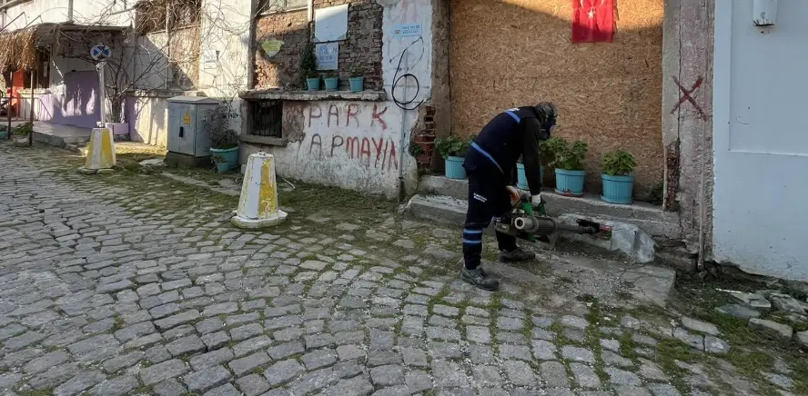 Belediye personeli tarihi bir binanın bodrum kat girişinde ilaçlama yaparken.