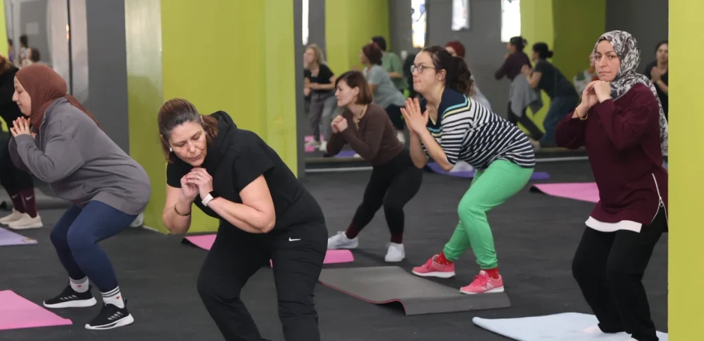 Hareketli müzik eşliğinde kardiyo ve aerobik yapan kadınların antrenman anı.