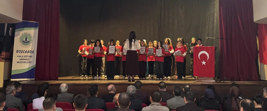 Bozcaada Halk Eğitim Merkezi sahnesinde düzenlenen 12 Mart oratoryo gösterisi ve dereceye giren öğrencilerin toplu görüntüsü.