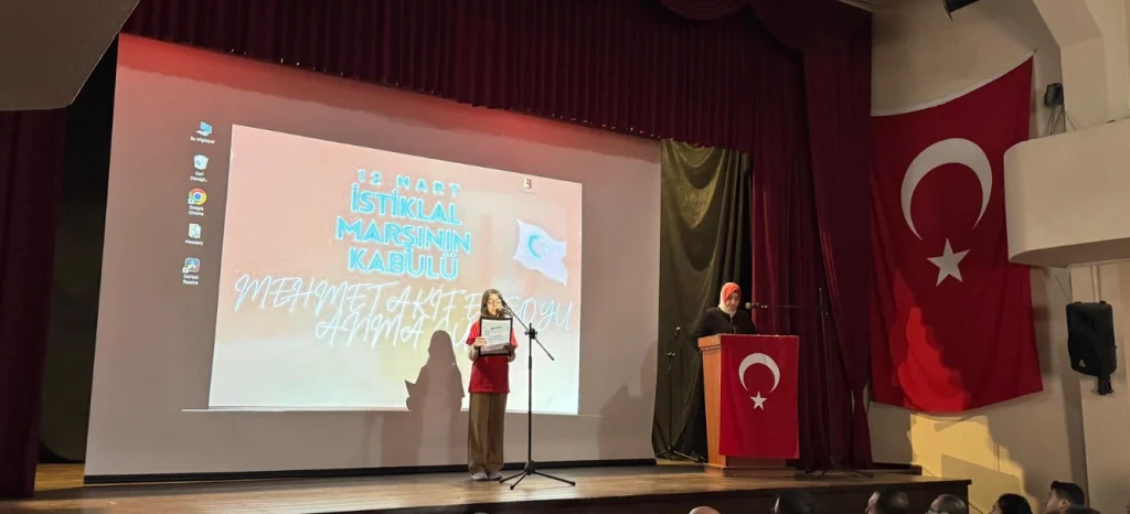 Bozcaada'da İstiklal Marşı'nın kabulü töreninde Türk Bayrağı eşliğinde sahnede şiir okuyan öğrenci ve Mehmet Akif Ersoy anma görselleri.