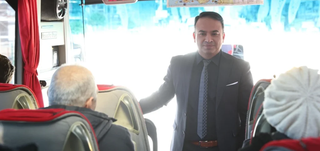 Belediye yetkilisi, Edirne yolculuğu öncesi otobüs içerisinde vatandaşlara gezi programı hakkında bilgi veriyor.