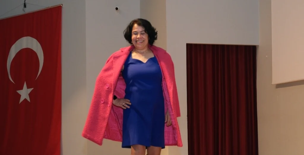 Uzunköprülü üretici bir kadının, kendi emeği olan mavi elbiseyi ve pembe paltoyu podyumda sergilediği an.