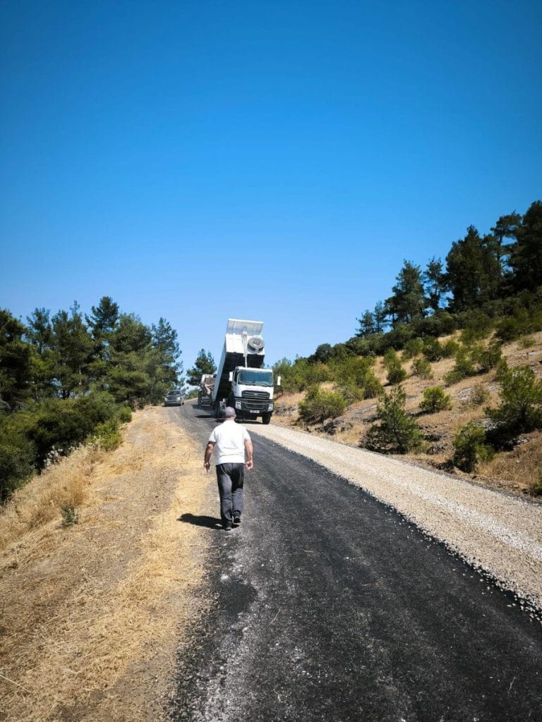 Lapseki Kızıldam Grup Yolu'nda asfalt sathi kaplama çalışması yapan iş makinesi